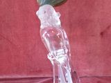 a glass figurine of a parrot with a green leaf on its head
