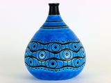 un vase bleu orné d'un motif, posé sur une table