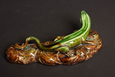 une figurine représentant un dragon posé sur un rocher, sur fond noir