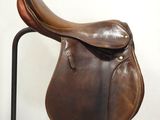 a brown saddle on a black stand against a white wall
