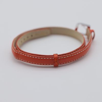 a close up of a red leather bracelet on a white surface