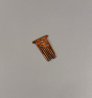 un petit peigne en bois posé sur une table, sur fond blanc