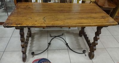 a wooden table with a metal base on a tile floor