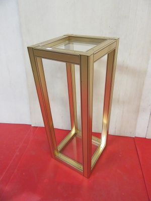 a gold metal frame with a glass top on a red floor