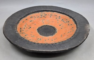 un bol noir et orange avec un trou au milieu