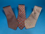 three ties on a blue background one has a red, the other has a green and yellow design