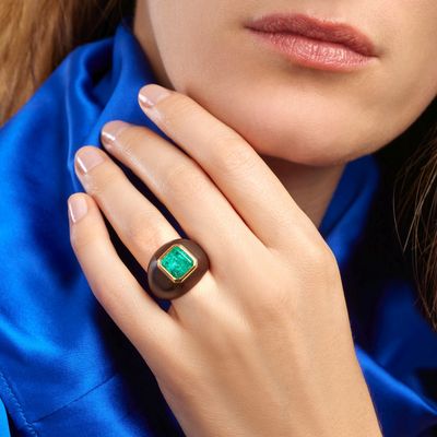 a woman wearing a ring with a green stone on it