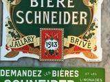deux enseignes sur le mur d'un immeuble où l'on peut lire « Bière Schneider »