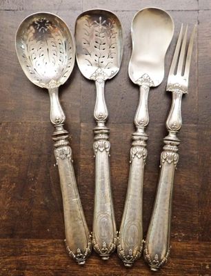 trois cuillères en argent et deux cuillères en argent posées sur une table en bois
