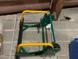 un chariot vert avec des outils posés par terre, à côté d'un tas de bois