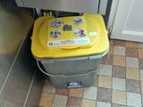 a yellow trash can sitting in the corner of a kitchen