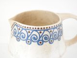 a white pitcher with a blue design on it