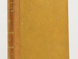 an old book sitting on top of a table next to a white wall