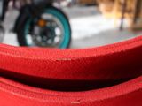 un gros plan sur un coussin de siège rouge avec une moto en arrière-plan
