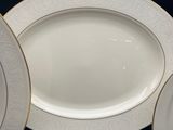 several white plates with gold rims are arranged on a black table
