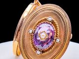 an image of a close up of a gold cuff with a purple stone