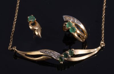 une photo d'un ensemble composé d'un collier et d'une boucle d'oreille en or, sertis d'émeraudes