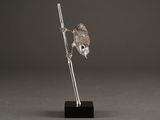 a silver figurine of a bird perched on a branch