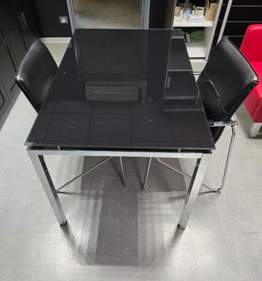 une table en verre entourée de quatre chaises dans une pièce