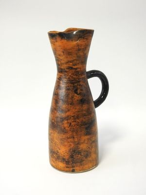 une cruche marron et noire posée sur une surface blanche