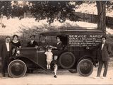 a black and white photo of a group of people standing in front of a truck