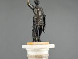 a bronze statue of a man holding a sword on top of a pedestal