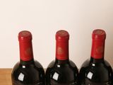 three bottles of red wine are lined up on a wooden table