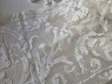 a white crochet on a bed with a teddy bear