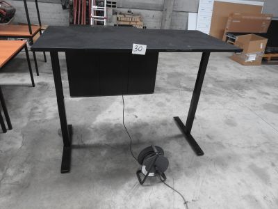 un bureau d'ordinateur sur lequel sont posés des écouteurs, dans un entrepôt