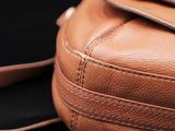a close up of a brown leather purse on a black background