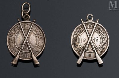 two silver medals with crossed swords on them on a black background