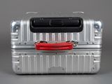 a silver suitcase with a red handle on top of it