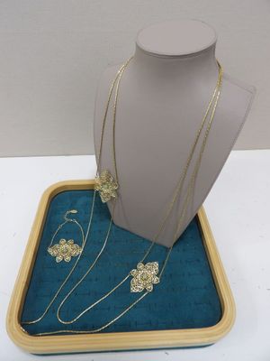 ensemble composé d'un collier et de boucles d'oreilles, présenté dans un coffret posé sur une surface blanche