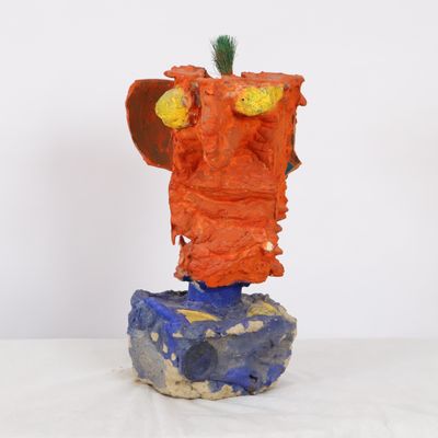 a sculpture of a face made out of clay on top of a rock