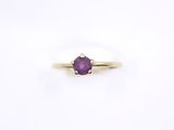 a close up of a yellow gold ring with a purple stone