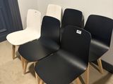 four black and white chairs are lined up against a white wall