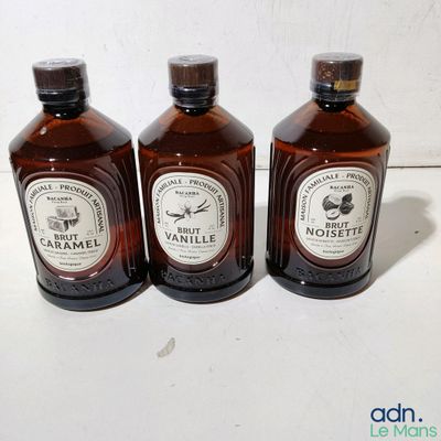 trois bouteilles de sirop posées les unes à côté des autres sur une table