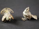 paire de figurines d'oiseaux de couleur argentée posées sur un fond noir