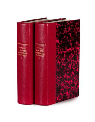 two red books sitting on top of each other on a white surface