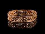 gros plan d'un bracelet en or sur une surface noire