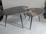 pair of black marbled tables with metal legs on a white floor