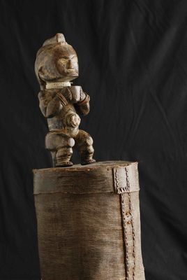 une image représentant une sculpture en bois d'un homme assis sur une botte