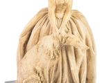 statue of a woman sitting on a sheep with a hat on
