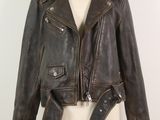une veste en cuir posée sur un mannequin, avec une ceinture autour