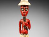 une figurine en bois représentant un homme avec un chapeau et une canne