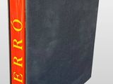 a book with a red cover sitting on top of a gray book