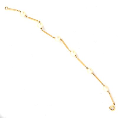 Le bracelet est en métal plaqué or et comporte une chaîne composée de perles blanches.