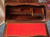 a small wooden desk with a red drawer in it