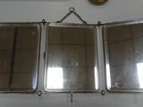 three mirrors hanging on a wall with a clock above them