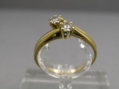 une image montrant un gros plan d'une bague en diamant posée sur une surface transparente